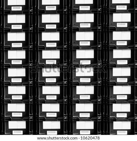 Stacks of black plastic shipping crates, with blank kan-ban labels and barcodes.  Automotive component shipping.