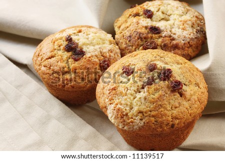 Home-baked cinnamon and sultana muffins, on beige linen.