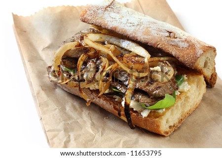Steak sandwich ~ toasted baguette with grilled beef and onions, on goat\'s cheese and spinach leaves.  On a brown bag, for a tasty lunch to go.