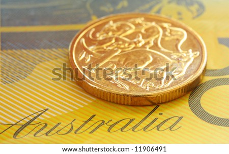 Australian one dollar coin on a fifty dollar note.  Close-up view, with shallow depth of field.