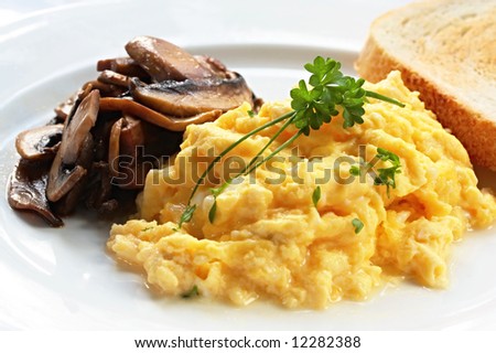 Breakfast of scrambled eggs, grilled mushrooms and toast.