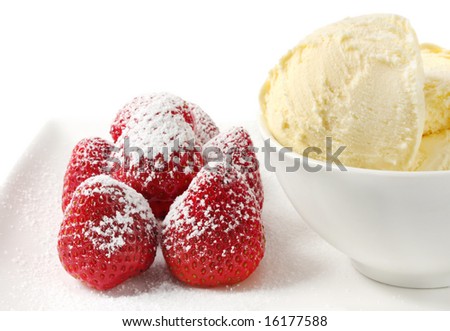 Luscious dessert with strawberries dusted with powdered sugar, accompanied by a bowl of rich vanilla icecream.