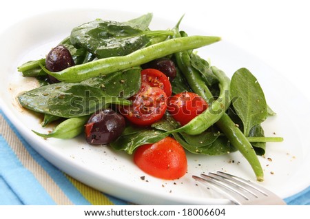 Salad of spinach leaves, chery tomatoes, green beans and black olives, with a balsamic dressing.