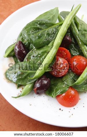 Salad of spinach leaves with green beans, cherry tomatoes, and black olives.  With black pepper and a balsamic dressing.