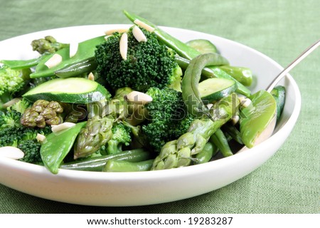 Serving bowl of mixed green vegetables, topped with toasted almond.  Delicious healthy eating.