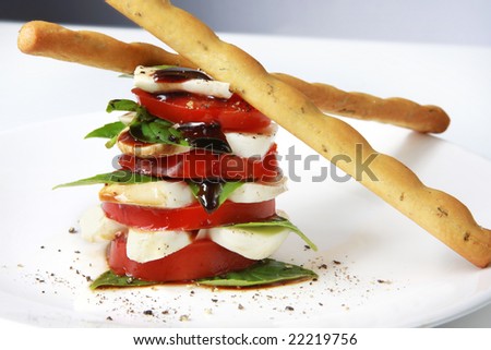 Caprese salad in a stack, with bread sicks.  Tomato and basil salad, with baby mozzarella and balsamic.