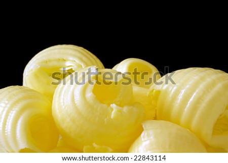 Butter curls in close-up, with black background.