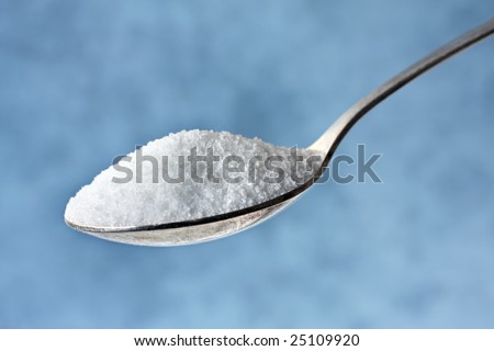 Spoonful of sugar, with blurred pastel blue background.