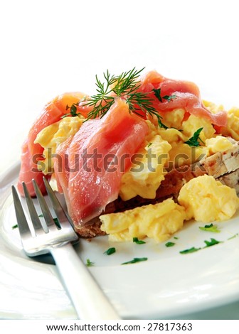 Smoked salmon over scrambled eggs and toast, garnished with dill and parsley.