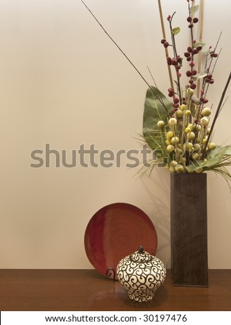 Interior still life.  Vase with dried flowers, with stylish bowl and plate on dark polished timber.