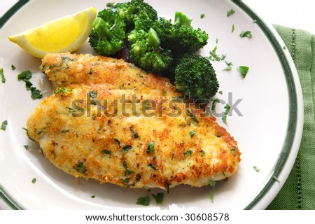Breaded and herbed chicken breast fillet, served with broccoli and lemon.  Delicious chicken schnitzel.