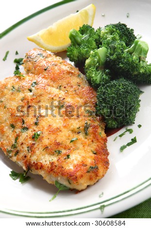 Breaded and herbed chicken breast fillet, served with broccoli and lemon.  Delicious chicken schnitzel.