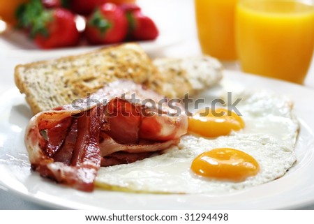 Bacon and eggs with toast, orange juice and fresh fruit.  Shallow DOF.