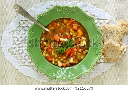 Bowl of vegetable soup, with crusty bread.  Overhead view.
