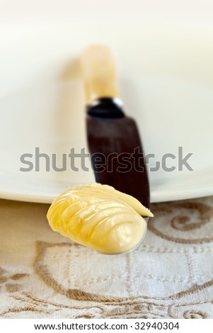 Butter on an old bone-handled butter knife, with focus on butter.