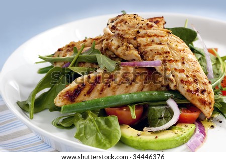 Salad of grilled chicken tenderloins with avocado, tomatoes, red onion, green beans, spinach and arugula.  Delicious healthy eating.