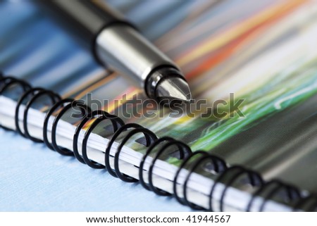 Fountain pen on colorful spiral notebook. Focus on tip of pen.