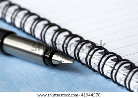 fountain pen on open spiral notebook.  Shallow depth of field, with focus on pen tip.
