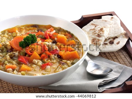 stock photo : Hearty vegetable soup with some flat bread, on a serving tray.