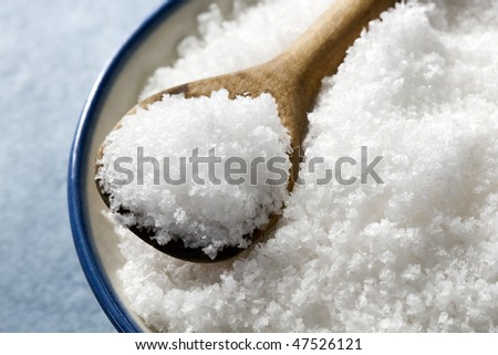 Bowl of sea salt flakes, with small wooden spoon.