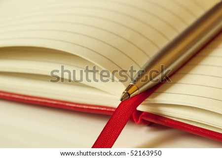 Ballpoint pen on an open red-covered book.  Shallow depth of field.