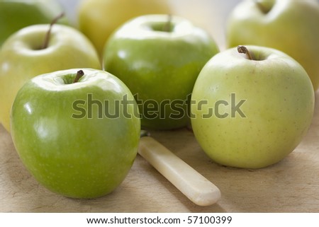Apples on an old chopping board, with bone-handled knife.  Includes Granny Smith and golden delicious varieties.
