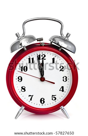 Old red alarm clock, showing two minutes to midnight.  Isolated on white.