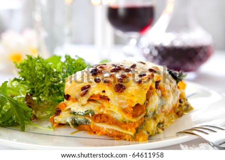 Vegetarian lasagne topped with toasted pine nuts and melting cheeses.  With salad and red wine.