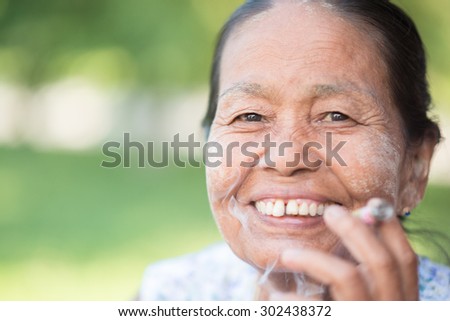 MANDALAY, MYANMAR - JULY 30, 2014 old wrinkled Asian woman smoking traditional tobacco. Bagan, Myanmar.