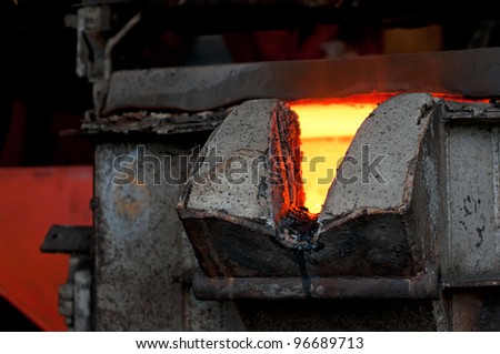 Molten metal is poured in a foundry. Hot metal