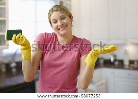 Young woman shrugs her shoulders while wearing dish gloves and holding a scrub pad.  Horizontal shot.