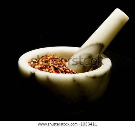 Red pepper flakes in marble mortar with pestle