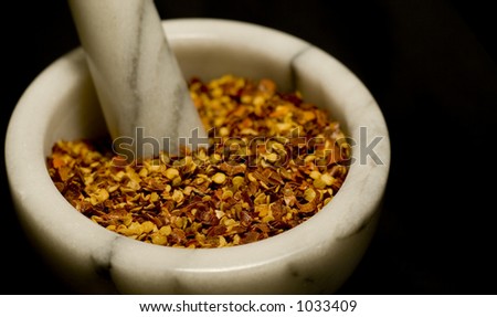 Red pepper flakes in marble mortar with pestle