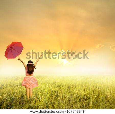 Beautiful Woman Holding Red Umbrella In Grass Field And Sunset