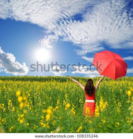 Woman holding red umbrella in Yellow flower field and cloud sky