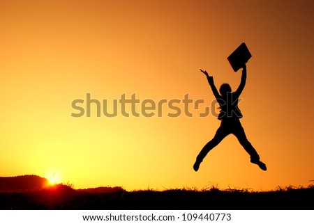 Business woman jumping and sunset silhouette