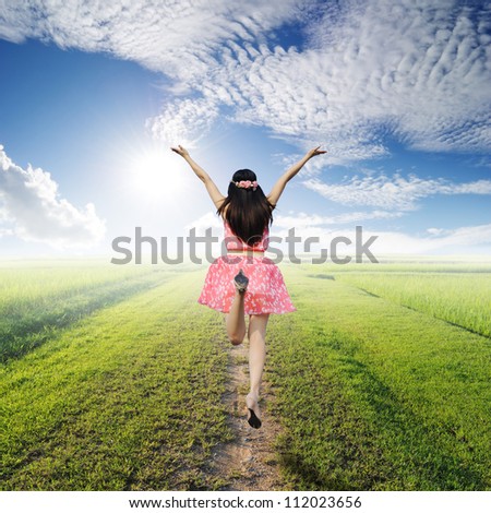 Happy woman jump on way of green grass and blue sky