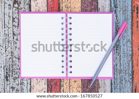 Open purple notebook and pen on vintage wood table for background and text