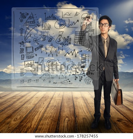 Business man writing concept business chart and standing  on Wood floor and blue sky mountain
