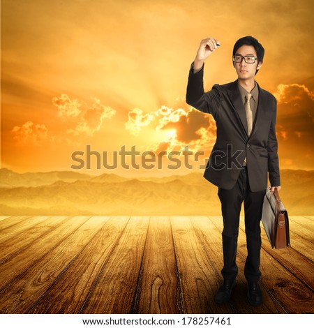 Business man writing  and standing  on Wood floor and sunset mountain