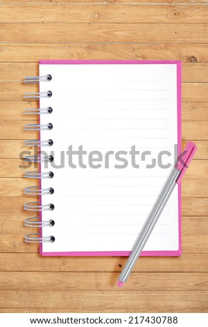 Open purple notebook and pen on  wood table for background and text
