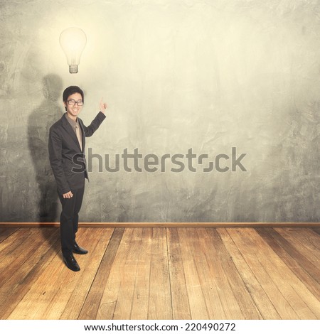 Business man thinking idea bulb and pointing on blank wall for text and background