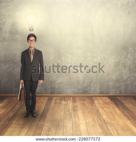Standing business man holding a briefcase  thinking idea bulb and blank wall for text and background