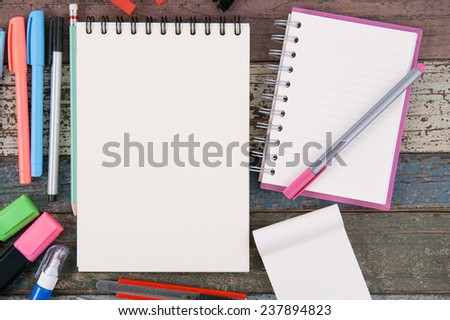 Notebook paper and school or office tools on vintage wood table background
