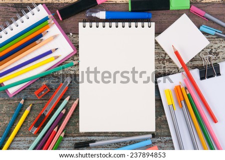 Notebook paper and school or office tools on vintage wood table background