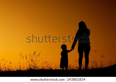silhouette of a mother and son  playing outdoors at sunset