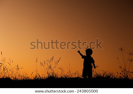 silhouette of boy  playing in grass field at sunset