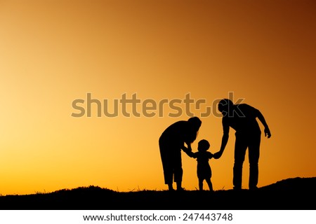 silhouette of  father mother and son playing outdoors at sunset