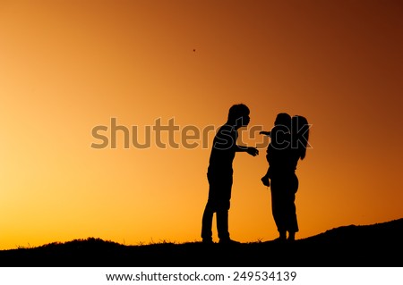 father mother and son playing outdoors at sunset silhouette