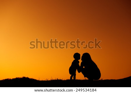 silhouette of a mother and son playing outdoors at sunset